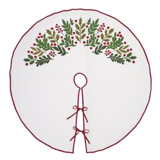 A round white Christmas tree skirt featuring a hand-embroidered holly and berry design across the top half, finished with a dark red stitched border and tie-on closure at the bottom.
