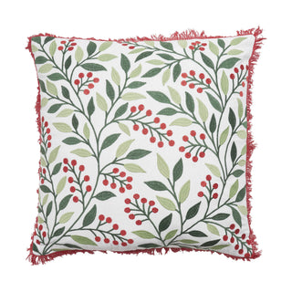 A square decorative throw pillow with a white background, featuring an all-over botanical pattern of green and light olive leaves with clusters of small red berries. The pillow has a red fringed edge and is shown against a plain white background.