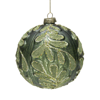 A green glass Christmas ornament with embossed leaf patterns and gold glitter accents, suspended by a gold string against a white background.