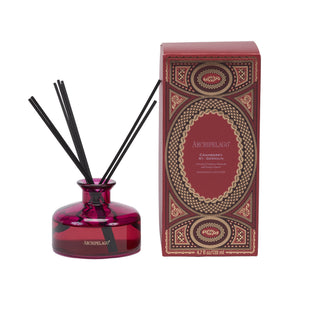 Archipelago Cranberry reed diffuser with a translucent deep red glass bottle and black reeds, shown next to its ornate red and gold packaging box on a white background.