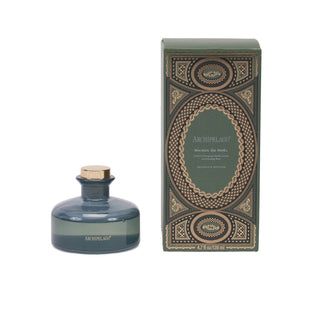 Archipelago reed diffuser bottle in smoky blue-green glass with a gold cap, shown next to its matching green and gold patterned box on a white background.