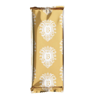 A single wrapped chocolate bar in shiny gold foil packaging with ornate white damask-style motifs and a large monogram letter B, centered on a plain white background.