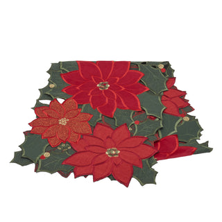 A festive holiday table runner featuring layered red poinsettia flowers and dark green holly leaves with small gold glitter accents, photographed on a solid white background.