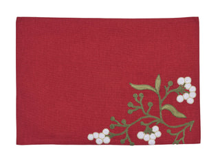A rectangular red fabric placemat featuring an embroidered branch of mistletoe with green leaves and white berries in the bottom right corner, shown against a plain white background.