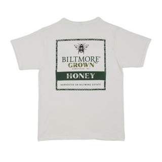 A white short-sleeve t-shirt with a green and black graphic print on the front reading 'BILTMORE GROWN HONEY HARVESTED ON BILTMORE ESTATE' with a bee illustration.