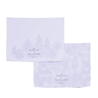 Two white cotton kitchen towels with a light winter forest pattern, featuring the Hallmark x Biltmore logo.