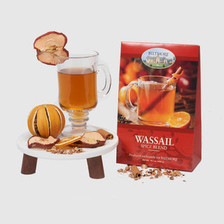 Wassail spice blend packaging with a glass of spiced tea and decorative elements on a white background