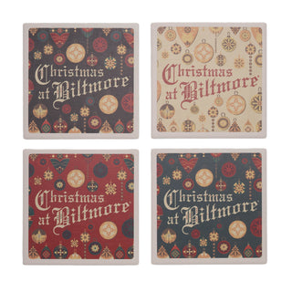Four square Christmas coasters arranged in a 2x2 grid on a white background. Each coaster features the phrase 'Christmas at Biltmore' in decorative lettering over a festive holiday pattern of ornaments, snowflakes, and geometric shapes in red, beige, and dark gray tones.