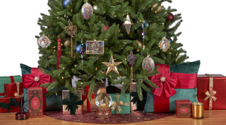 A decorated Christmas tree with ornaments, lights and accents inspired by Biltmore Estate's Tapestry gallery. The bottom part of the tree is surrounded by wrapped gift boxes and pillows against a white background.